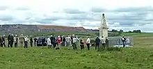 personnes groupées autour d’un monument dans la campagne