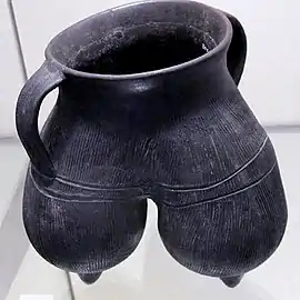 Vase à anses, tripode. Terre cuite grise à lustrage noir, décor excisé. H: 20 cm env. Longshan (sans précision) , 2000-1700. Victoria and Albert Museum