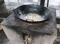 Un wok sur un poêle à bois extérieur.
