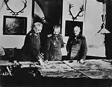 Photographie ancienne de trois militaires travaillant sur une carte.