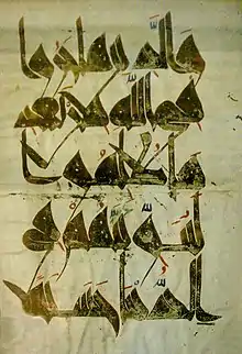 Calligraphie coufique caractéristique sur un feuillet du Coran.