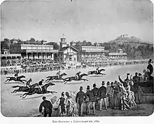Photographie d'une gravure en noir et blanc représentant des spectateurs devant un champ de course au premier plan, la tribune d'un hippodrome au deuxième plan et un mont à l'arrière-plan.