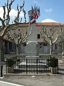 Monuments aux morts, l’obélisque de pierre entouré d’une petite grille est pavoisé. Il est situé devant l’école dont la cour est planté de platanes.