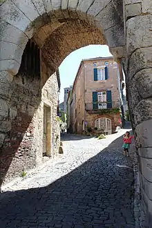 Photo couleur de la côte vers la ville à travers l'ouverture de la porte. Le sol est pavé et derrière l'appareillage en pierre, des portions en briques sont visibles.