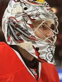 Photographie en gros plan d'un gardien de but de hockey sur glace avec un maillot rouge et un casque blanc