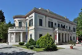 Vue d'une villa blanche, avec des colonnes sur une partie de sa façade.