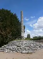 Photographie en couleurs d'une colonne en pierre dans un cimetière.