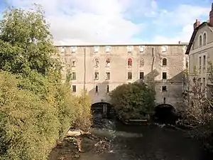 Photographie en couleur d'un bâtiment ruiné au dessus d'une rivière.