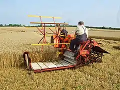 Moisson de blé avec une moissonneuse-lieuse Massey-Harris (avant 1940) peu différente des machines tirées par des chevaux ; reconstitution de 2008.