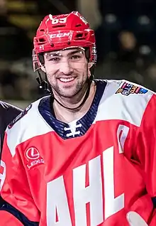 Photographie d'un joueur de hockey sur glace avec un maillot blanc frappé une tête d'un soldat romain.