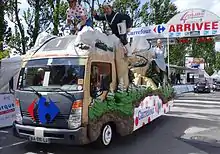 Camion noir et beige pour Carrefour, vu de trois-quarts, dépassant la ligne d'arrivée.