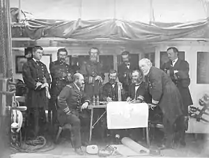 Une photographie d'officiers de la marine américaine tenant un conseil de guerre à bord du vaisseau amiral de l'Asiatic Squadron sur la frégate à vapeur USS Colorado, au large de la Corée en juin 1871 avant l'expédition de Corée. Pillsbury, photographié en maître, se tient à gauche.
