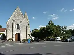 Photographie en couleurs d'une église au clocher en pierre et la place adjacente.