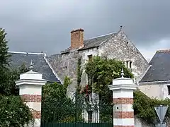 Photographie en couleurs d'un bâtiment dont un mur est composé d'une alternance de damiers en pierres et en briques.