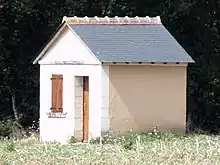 Photographie en couleurs d'une petite maison isolée au milieu des champs.