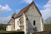 Le chœur de l'église en pierre calcaire avec une ouverture de style roman.