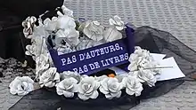 Au milieu de la couronne mortuaire faite de fleurs de papier se lit le message, écrit en blanc sur fond bleu : "Pas d'auteurs, pas de livres".