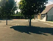 Photographie en couleurs d'une cour avec des dessins sur le sol goudronné.