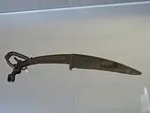 Couteau xiao à tête de bouquetin ibex. Nord ou Nord-Ouest de la Chine trouvé au Shanxi. Bronze. XIIIe – XIe siècle av. J.-C.. Musée Cernuschi