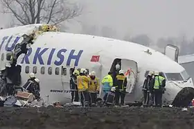 Un avant de fuselage brisé et une douzaine de sauveteurs autour.