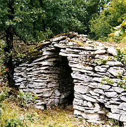 Abri de vigneron en pierre sèche dans une clôture.