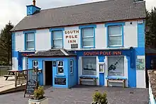 Photographie couleur du South Pole Inn, une bâtisse blanche et bleue.