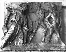 Image d'une sculpture en bas relief sur marbre montrant sur la partie gauche un homme âgé auréolé, drapé dans une longue tunique chassant d'un geste, au centre un homme nu de dos et à droite une femme nue de profil qui s'éloigne.