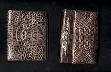 Deux porte-monnaie en cuir où on distingue les scutelles caractéristiques des crocodiles, sur fond noir.