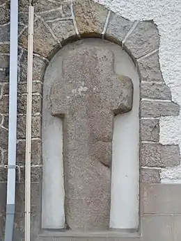 Photo d’une croix encastrée dans un mur de maison.
