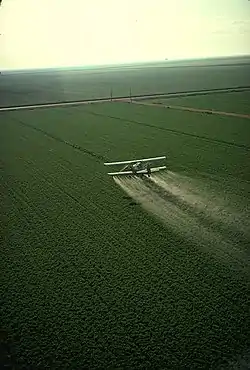 Système de pulvérisation intégrée dans un avion biplan, épandage d’herbicide en Californie.