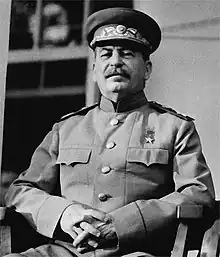 Photographie en noir et blanc du chef d'état soviétique assis sur une chaise, en tenue militaire.