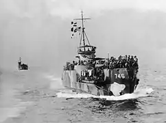 Photo en noir et blanc d'un navire de débarquement au pont rempli de soldats