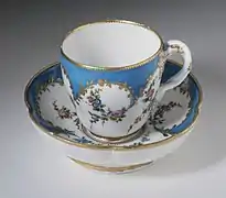 Une soucoupe et une tasse en porcelaine blanche et bleue, à motifs de fleurs.