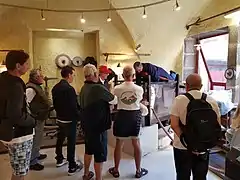 Photographie d'une démonstration d'émouture au musée de la coutellerie avec quelques personnes qui regardent le coutelier.