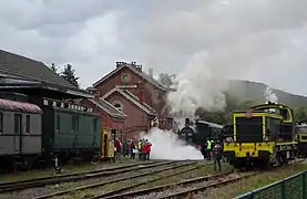 Festival 2018 : Ambiance vapeur à Treignes. La locomotive a vapeur AD05 démarre en purgeant ses cylindres. La fumée d'une autre locomotive à vapeur est visible derrière la locomotive diesel BB 63.149.