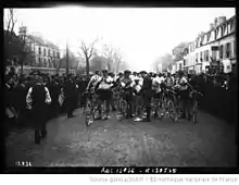 Photographie en noir et blanc présentant des cyclistes au départ d'une course.