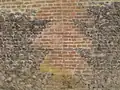 Détail de mur de ferme :motif de briques dans soubassement en silex.