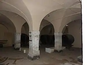 Photographie d'une cave ancienne dont les voûtes s'appuyent sur des piliers de maçonneries massifs.