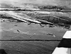 Photo aérienne de Gold Beach le 6 juin 1944. La batterie du Mont Fleury (WN 35a) et le fossé anti-char (en forme de large chevron) sont visibles en face du village de Ver-sur-Mer.