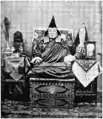 Lama mongol de Lhassa, au Tibet, vers 1905, reposant sur une caisse comportant les deux formes de shou.