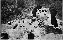 Photographie ancienne des fouilles d'une nécropole de Carthage avec divers artefacts dont des ossuaires encore en place