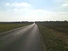 Une route droite jusqu'à l'horizon dans un paysage de champs ouverts