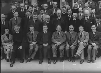 Photo en noir en blanc d'un groupe de scientifiques, comportant presque exclusivement des hommes.