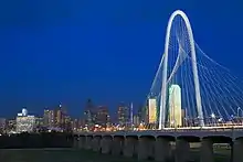 Photo de nuit d'un pont au-dessus du fleuve Trinity et des bâtiments de la ville de Dallas, dans le fond