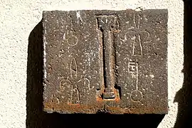 Dalle en pierre de Volvic comportant au centre une colonne avec chapiteau, entourée des armes de l'abbaye de manière alternée