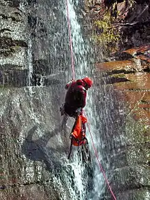 plan moyen d'un canyoniste avec son sac en dessous de lui