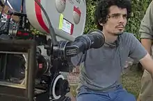 Damien Chazelle assis derrière une caméra, qui est en premier plan.
