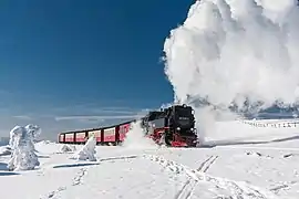 Un train à vapeur trace son chemin au milieu de volutes de neige.