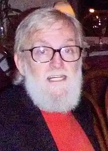 Photo d'un homme aux cheveux et barbe grise qui porte des lunettes.