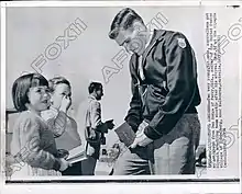 Un homme brun signe des autographes auprès d'enfants.